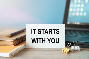 IT STARTS WITH YOU - an inscription on a card near office supplies and computer